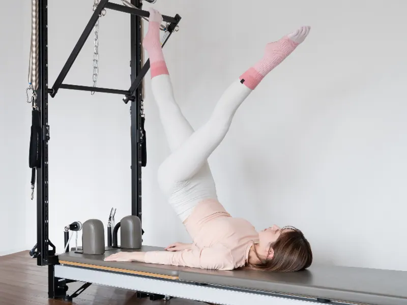 Leg work on the Pilates Tower, lying on the mat with both legs raised
